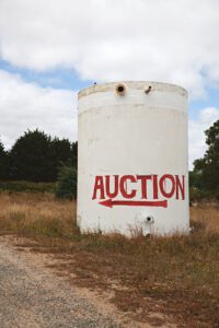 A large cylindrical tank with an "Auction" sign direction