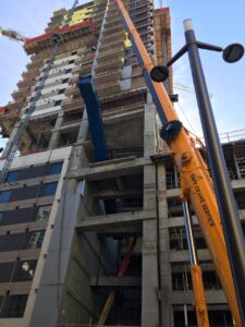 A crane lifting an escalator into a building using rigging from LGH
