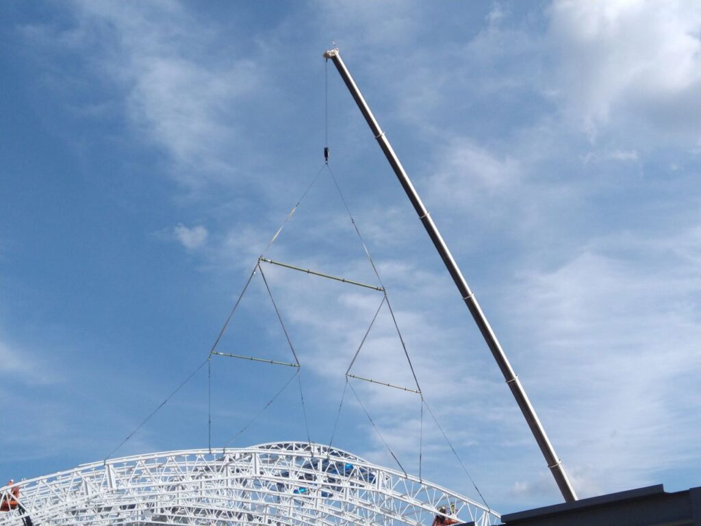 Modular lifting spreader beam rentals from LGH, under the hook of a crane lifting a large load.