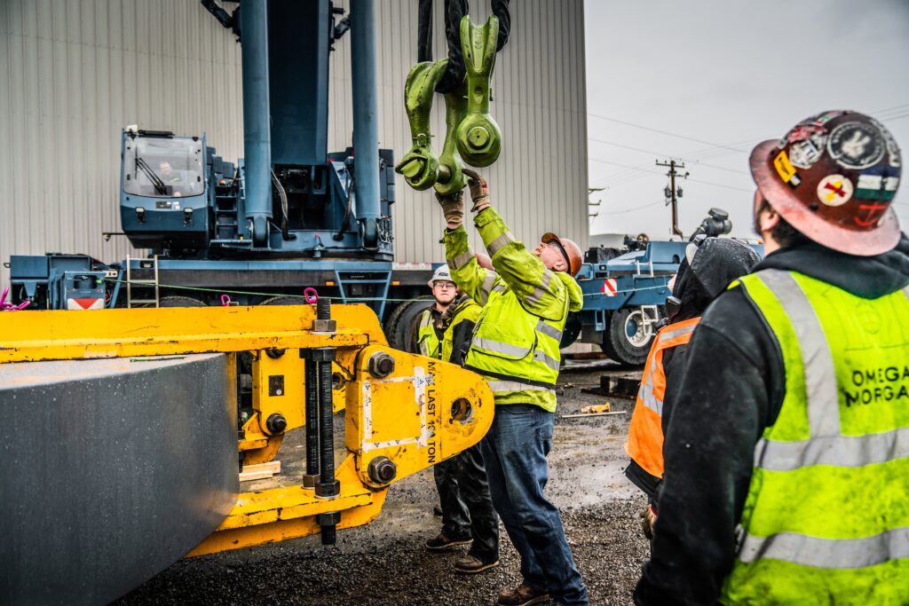 Construction workers on a jobsite attaching a rigging shackle to a sling.